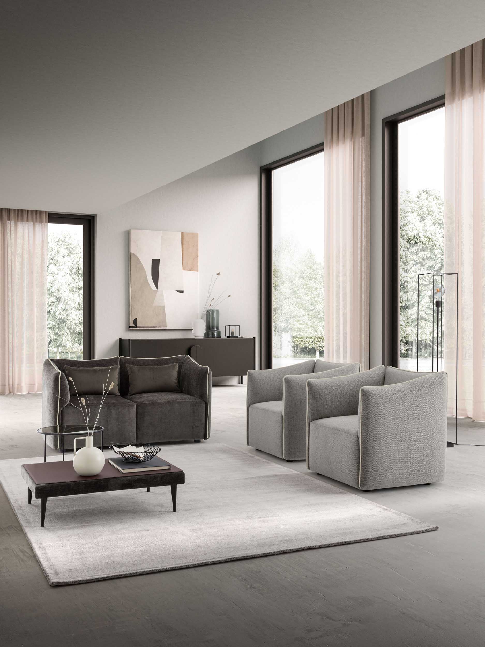 Ambiente arredato con loveseat grigio scuro con cuscini imbottiti e poltrone