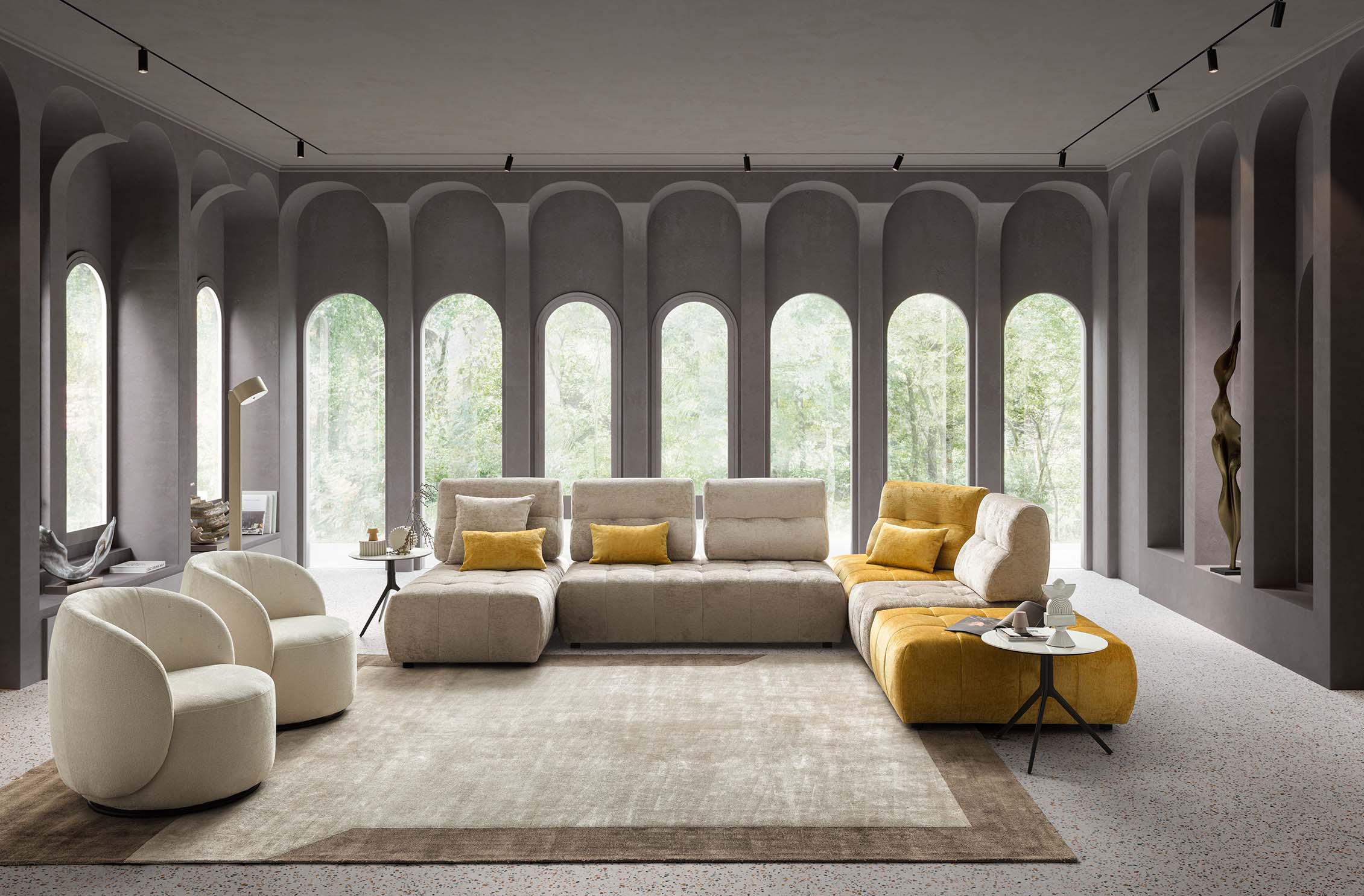 Soggiorno composto dal divano modulare trapuntato Byron disposto a L con una chaise longue e due poltroncine moderne. Colori panna e giallo.