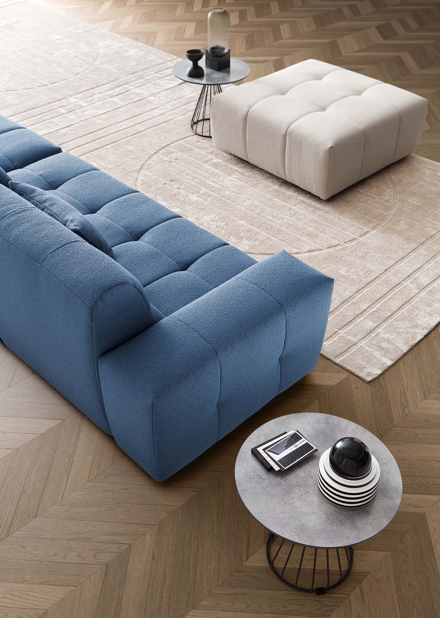 Composizione di un divano modulare con modulo lineare e isola a se stante che può fungere da pouf.