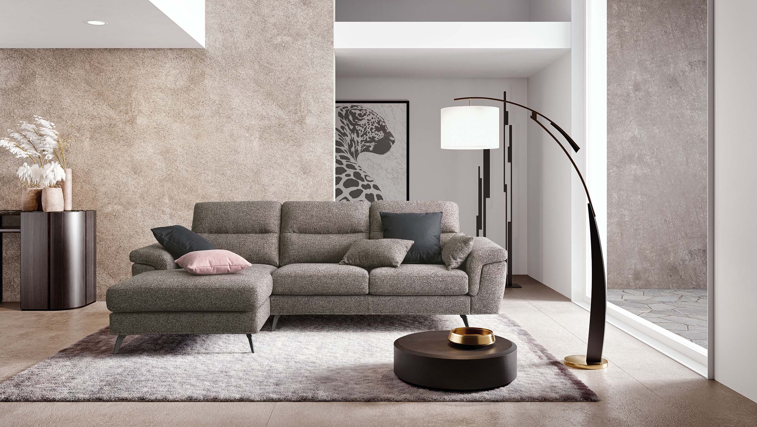 Divano elegante di colore grigio con piattaforma laterale e braccioli arrotondati.