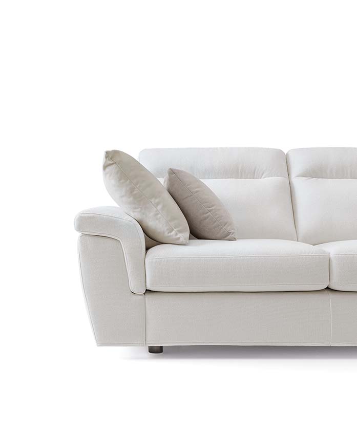 Divano bianco con schienali alti e piedini bassi dalle forme moderne e accoglienti.