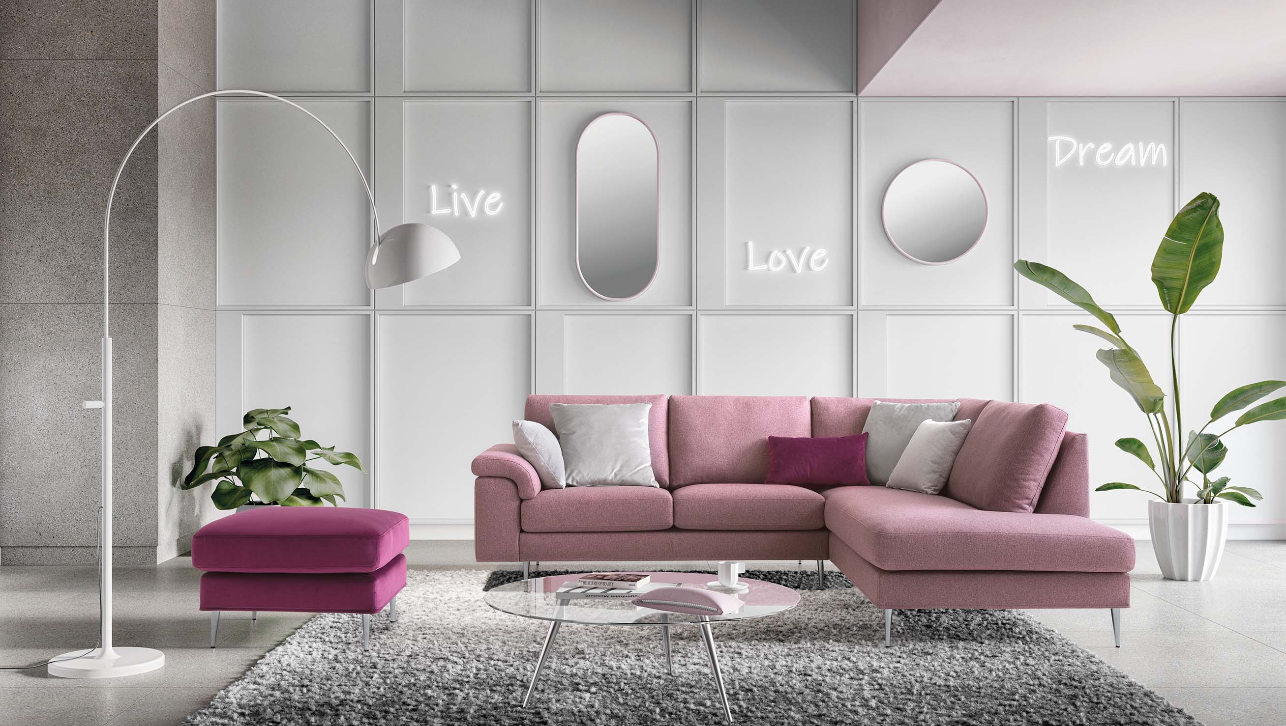 Soggiorno minimalista con divano a penisola colore rosa confetto, piedini alti e schienali imbottiti. Pouf colore fucsia.