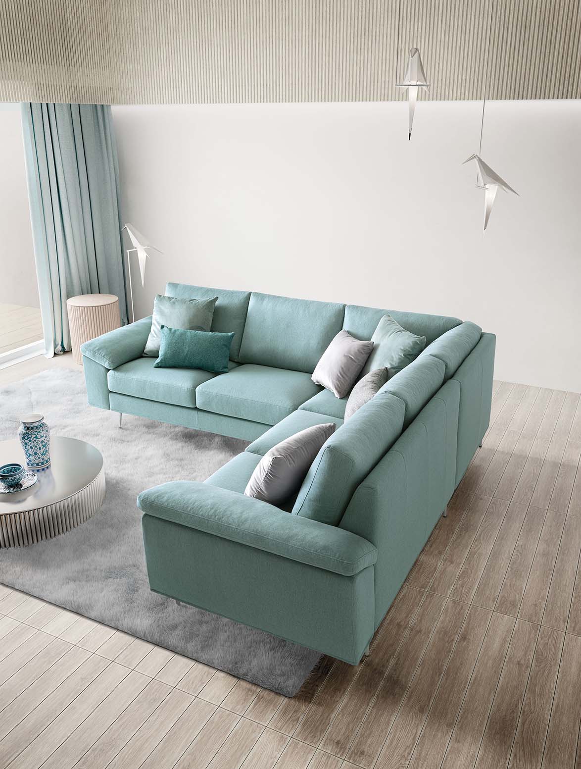 Divano moderno con rivestimento in colore verde acqua e cuscini grigi e verde petrolio a contrasto.