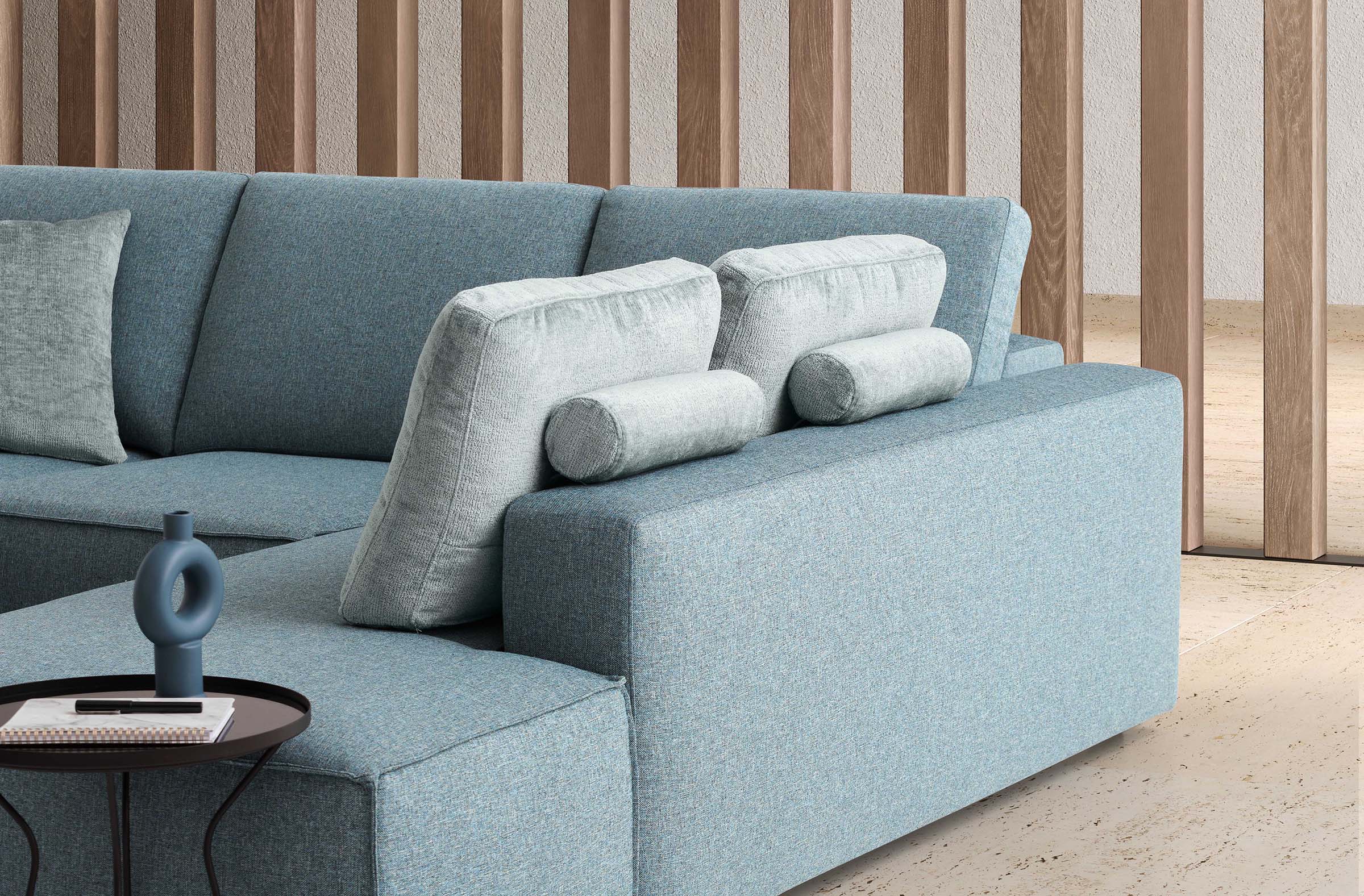 Divano con chaise longue che diventa uno schienale grazie a due cuscini appoggiati alla struttura angolare.