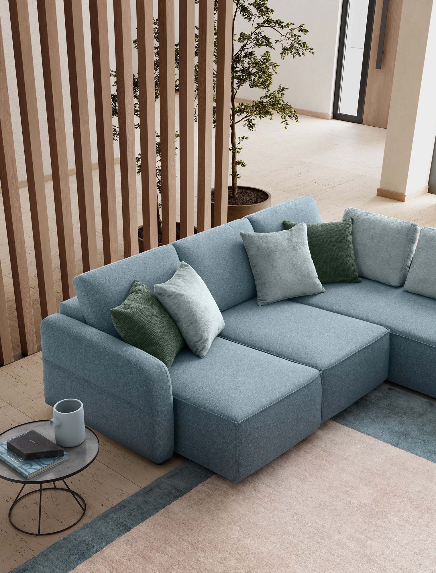 Sofà con sedute estraibili ampie a tre posti. Colore azzurro con cuscini verdi e celesti e bracciolo trapuntato.