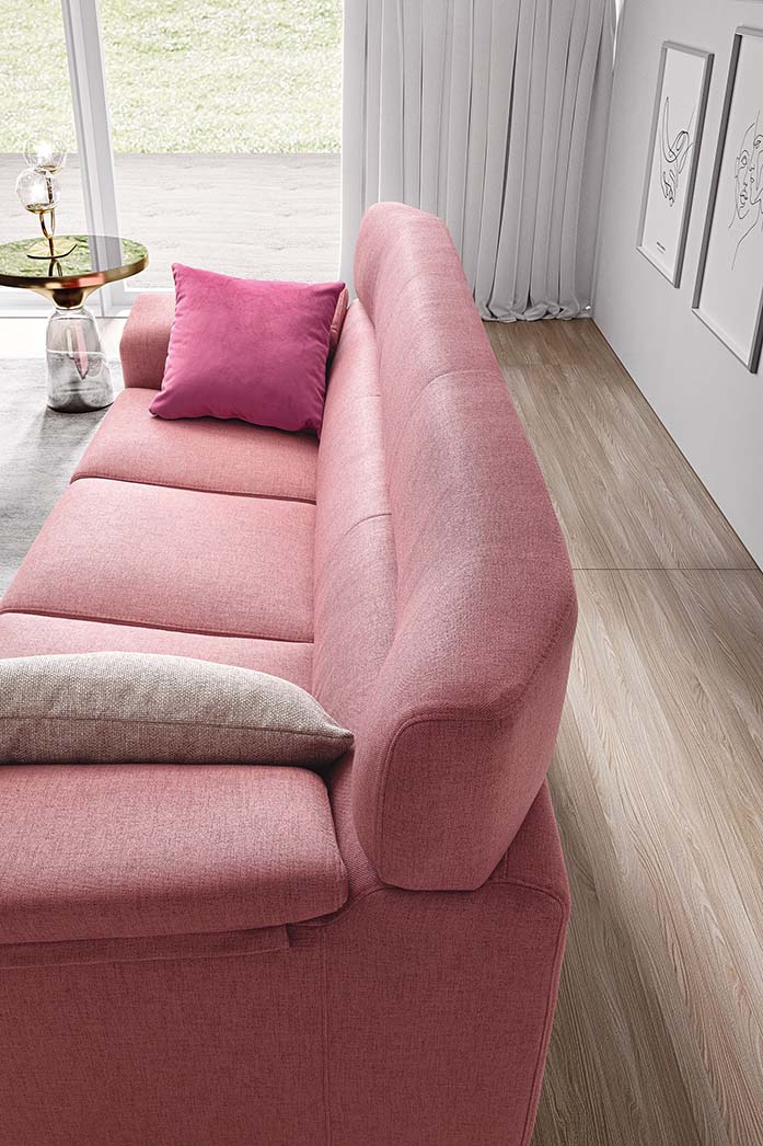 Divano color rosa cipria con seduta ampia e schienale alto adornato da due cuscini fucsia e panna