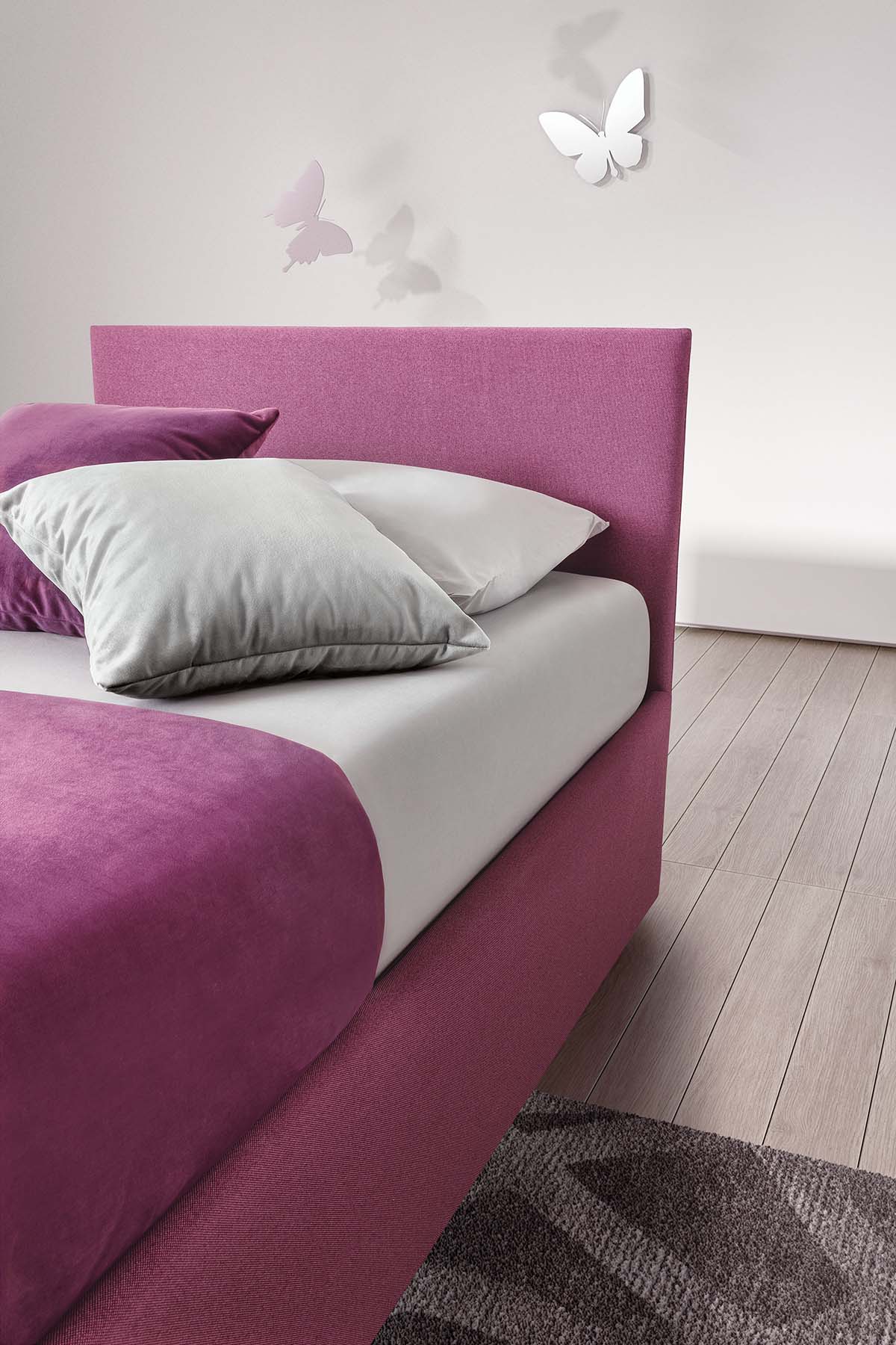 Dettaglio della testiera super sottile di un letto singolo color rosa e cuscini color argento