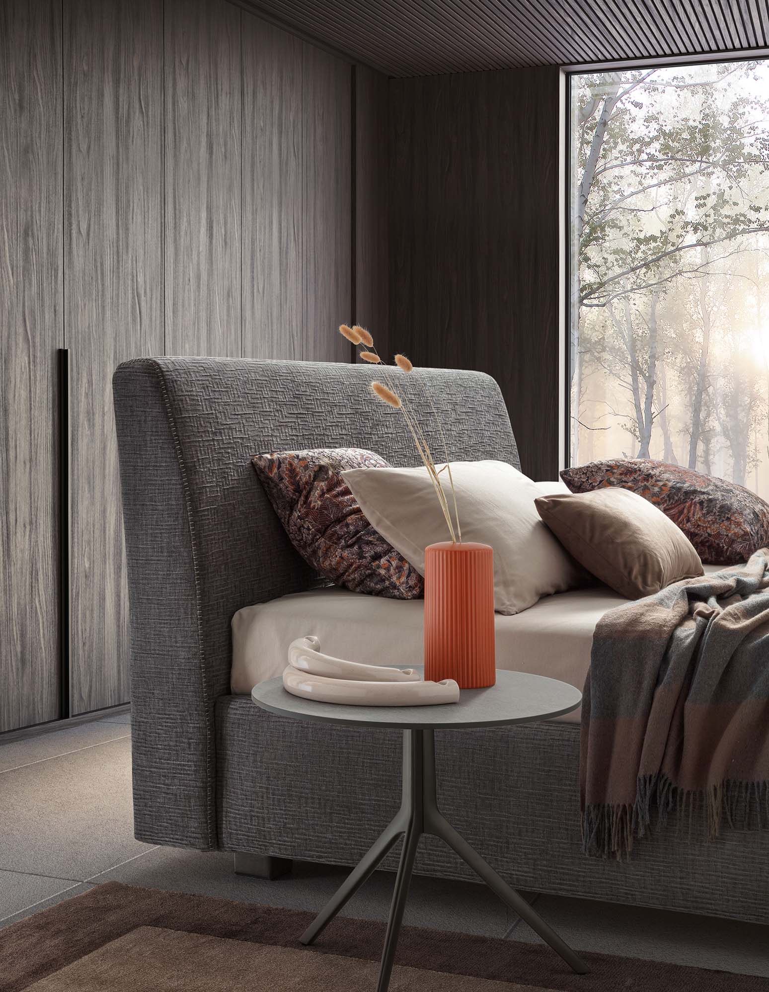 Letto grigio imbottito inserito in una stanza moderna e minimal con tavolino abbinato
