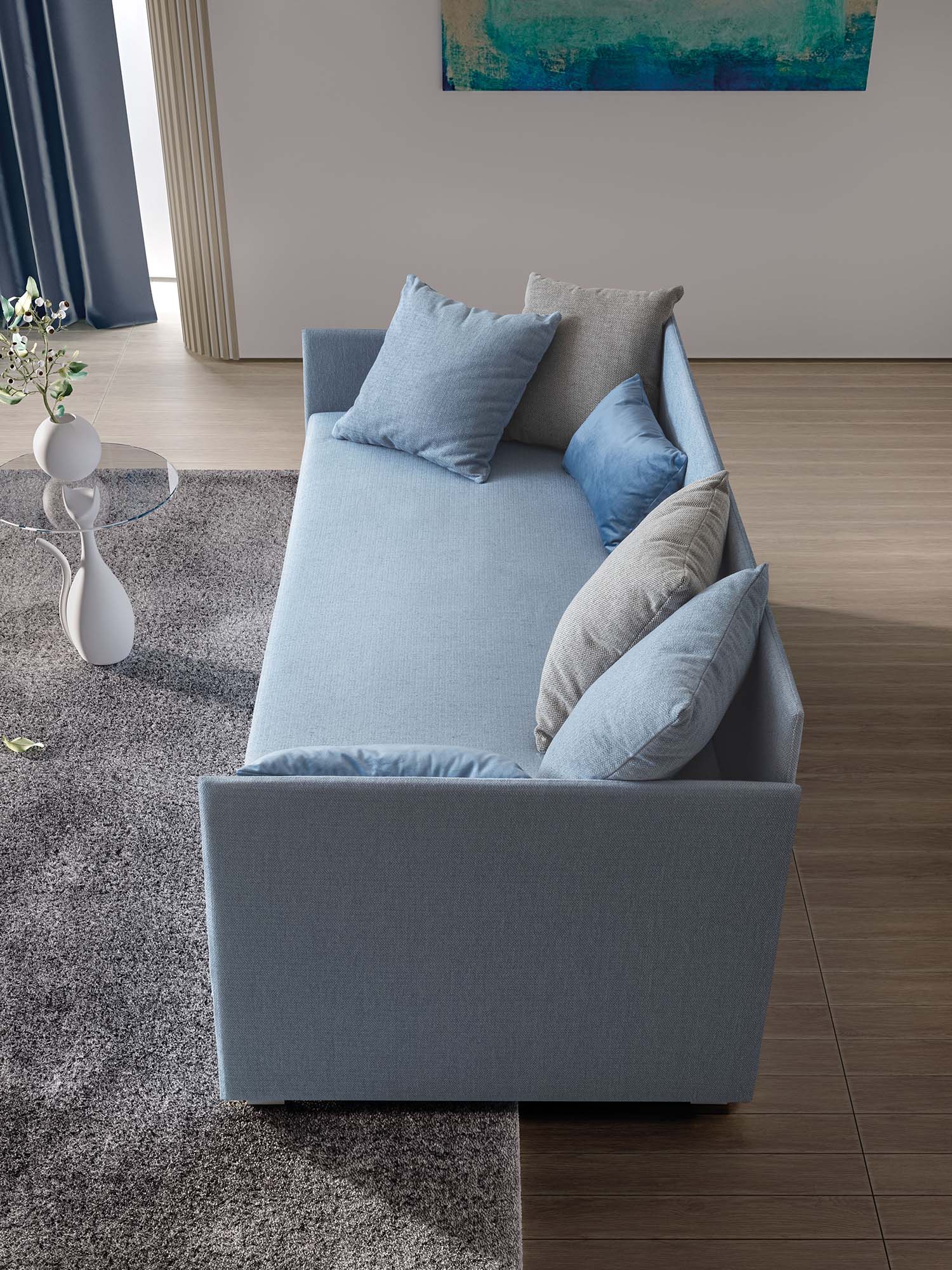 Daybed in modalità divano con struttura molto sottile. Tessuto color azzurro pastello con cuscini comodi
