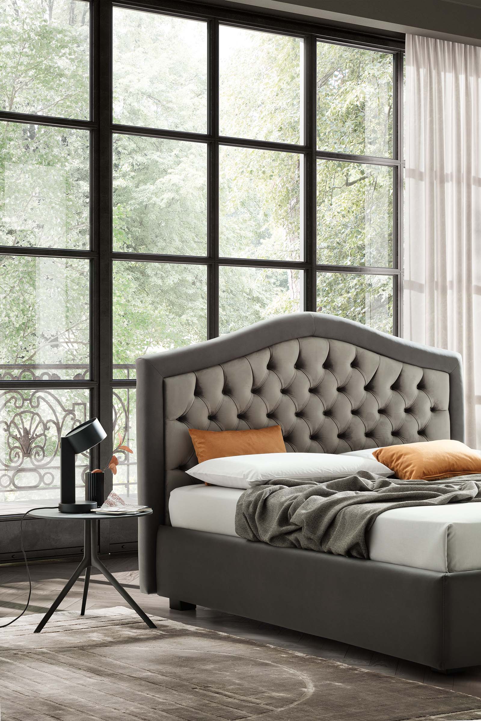 Stanza con ampie vetrate arredata con letto stile chesterfield grigio e tavolino abbinato