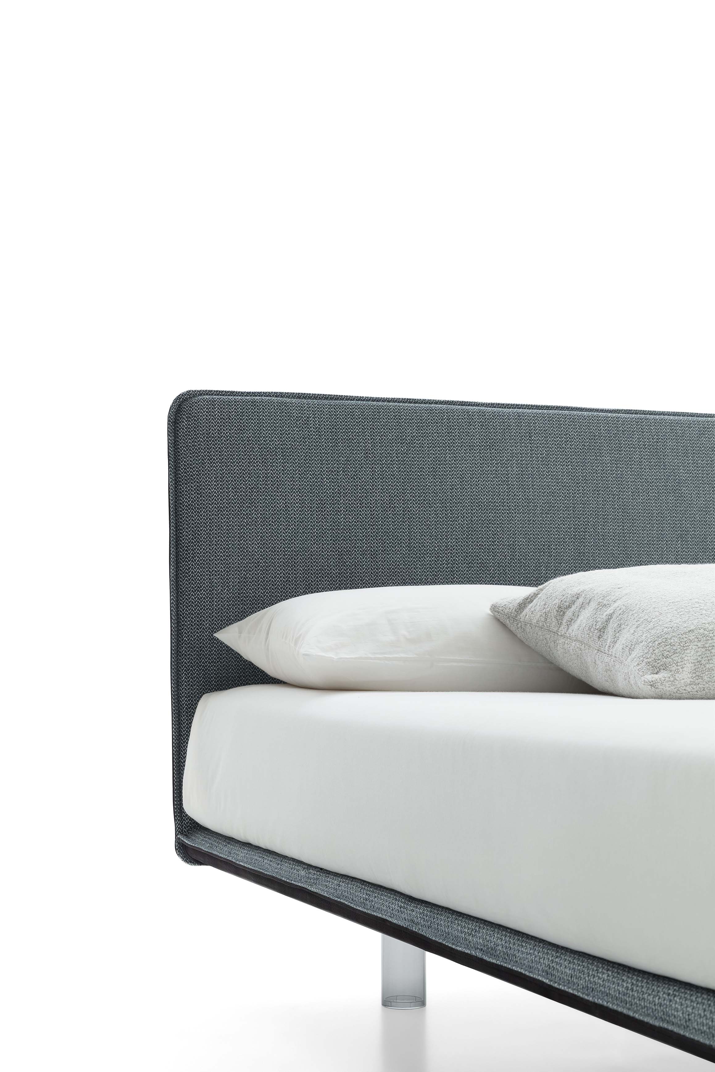 Dettaglio della testiera sottilissima di un letto di design con piedini trasparenti
