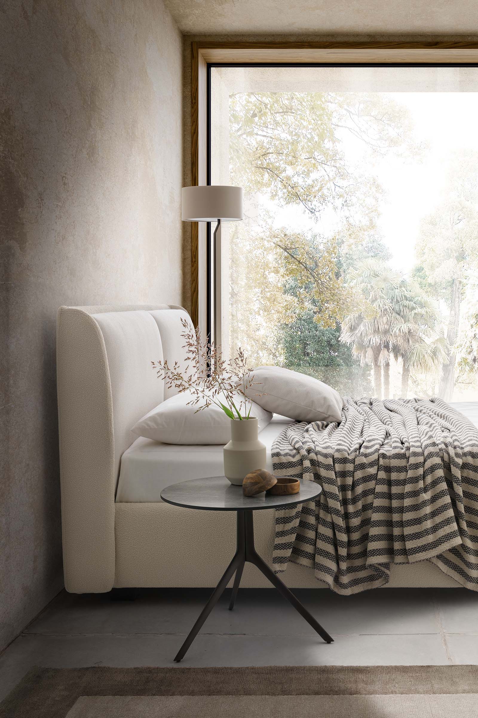 Stanza luminosa arredata con letto matrimoniale bianco basso e robusto