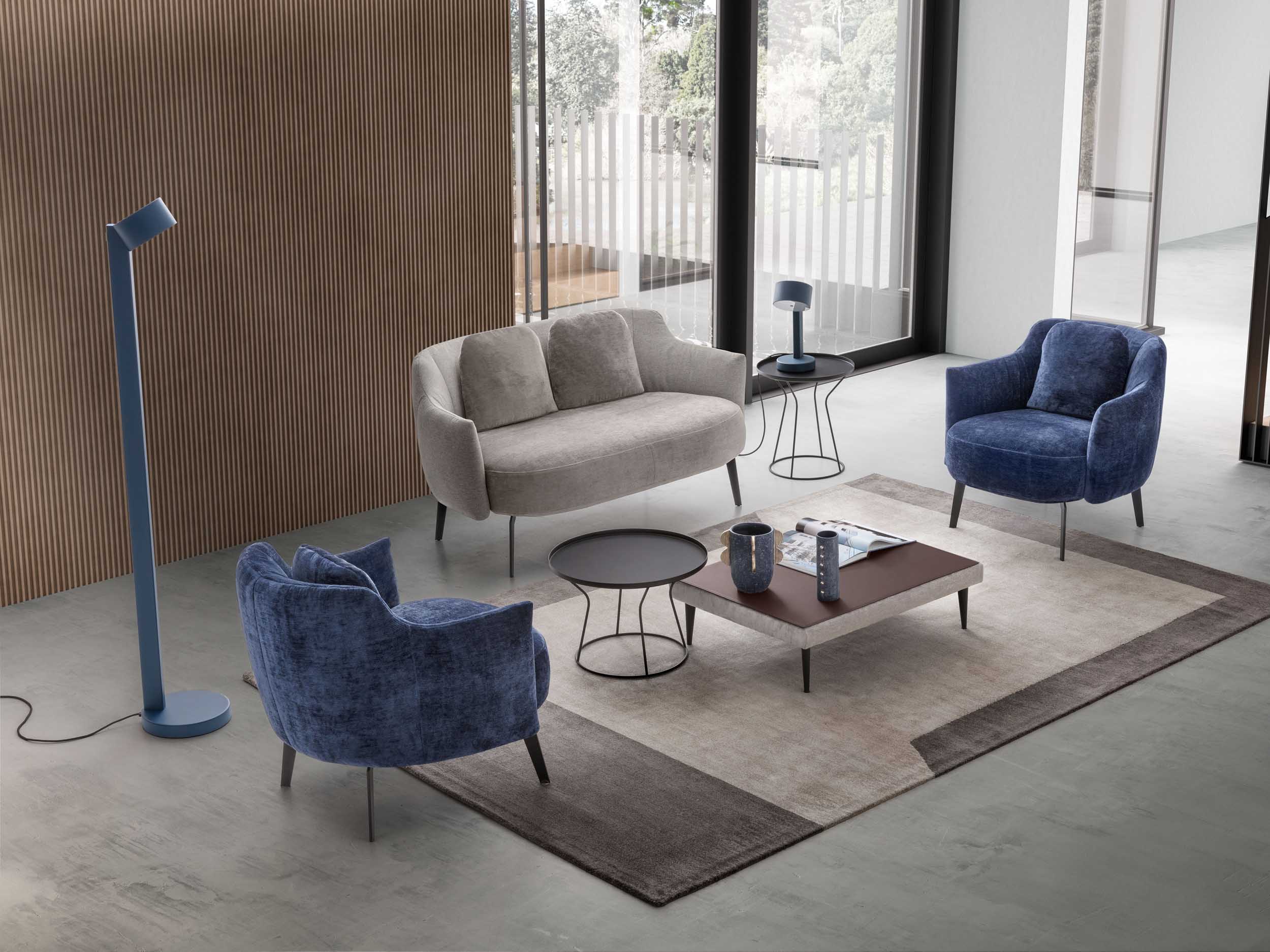 Salottino moderno con due poltroncine blu e un divano a due posti argento.
