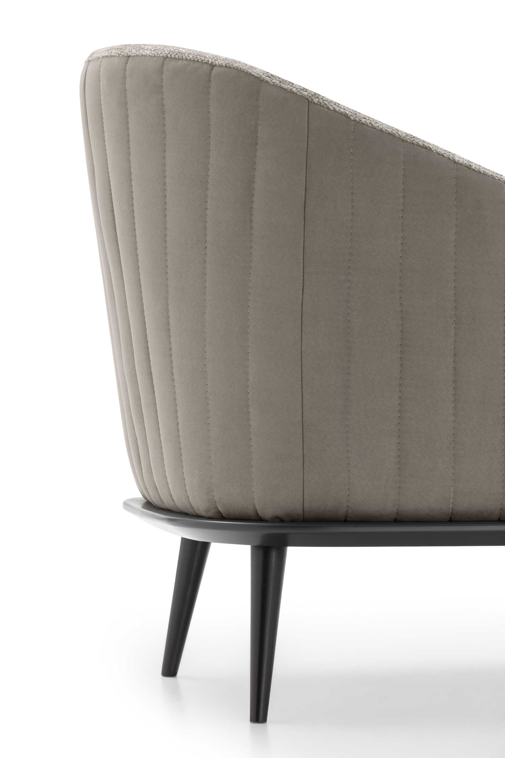 Trapuntature a strisce verticali sul retro di una poltroncina con piedini moderni neri