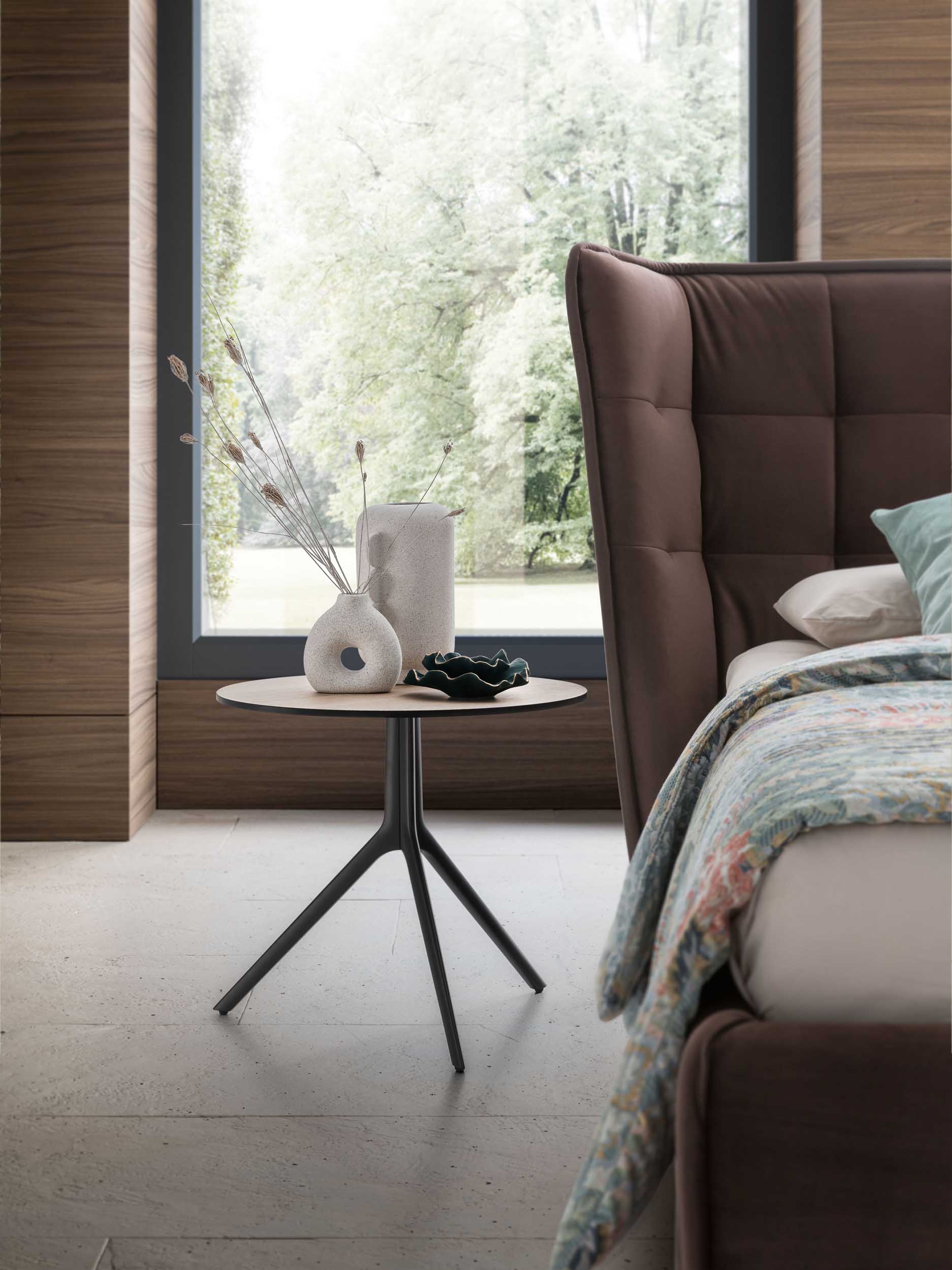 Tavolino di design posto al lato di un letto come comodino